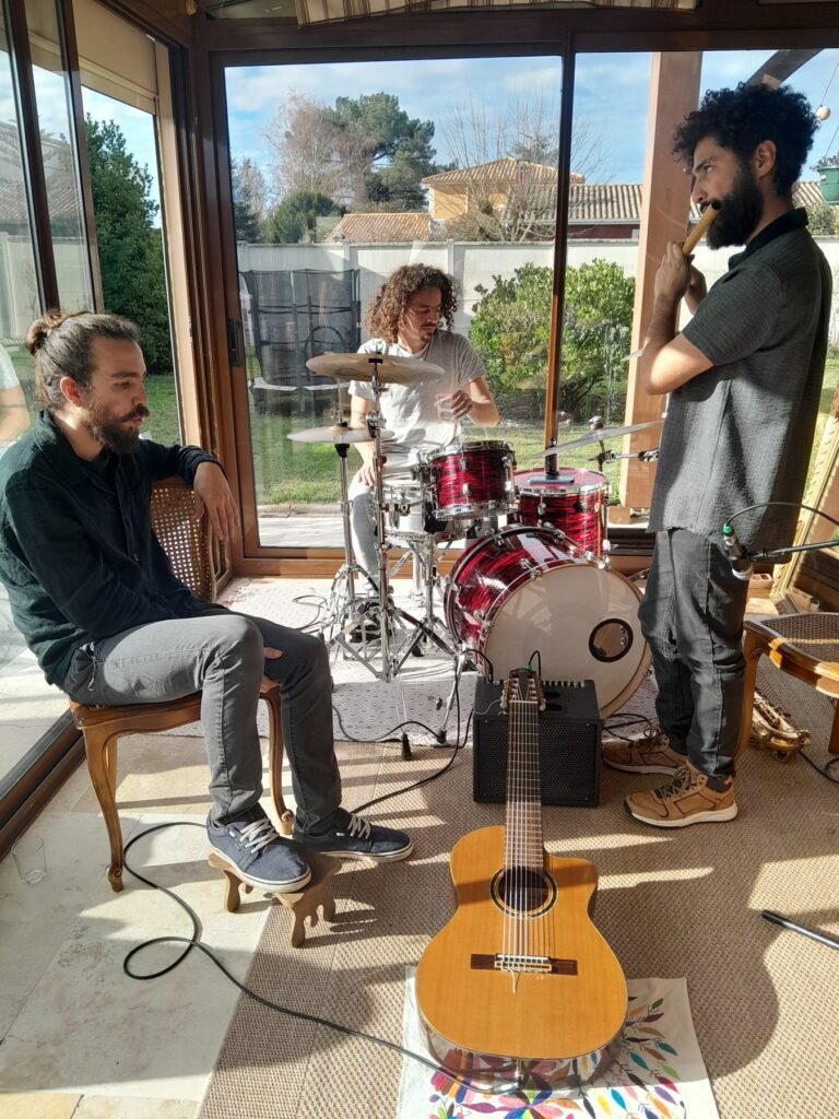 Urracas Trío en répétition : guitare, batterie et flûte dans une véranda ensoleillée
